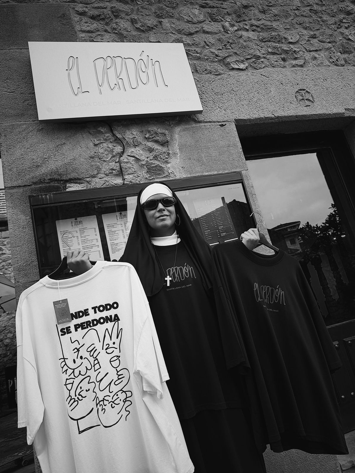 Camisetas de El Perdón colgadas bajo el rótulo de la fachada